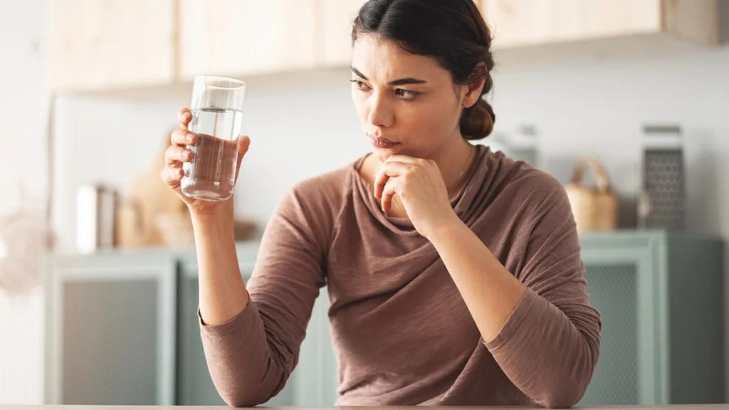 Homeowner concerned as water smells like rotten eggs while holding a glass from the tap