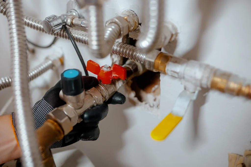 Corroded shutoff valve behind toilet in danvers: technician working on water line valves and plumbing connections