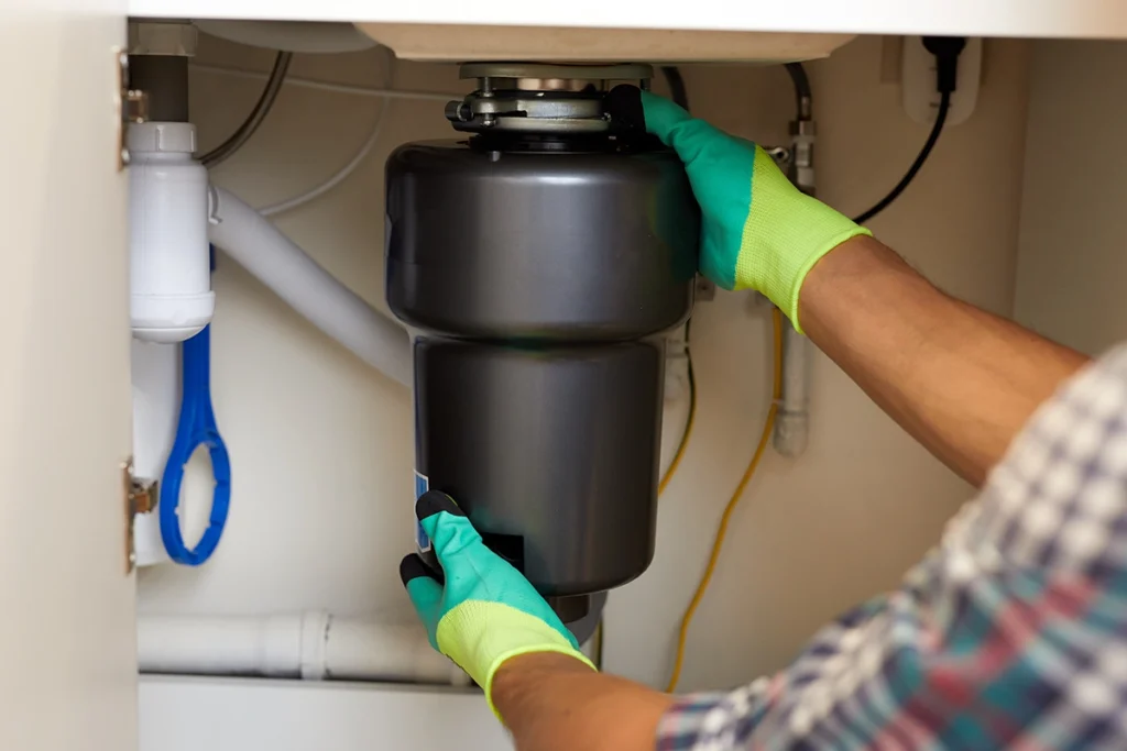 Technician installing or replacing an under-sink garbage disposal.